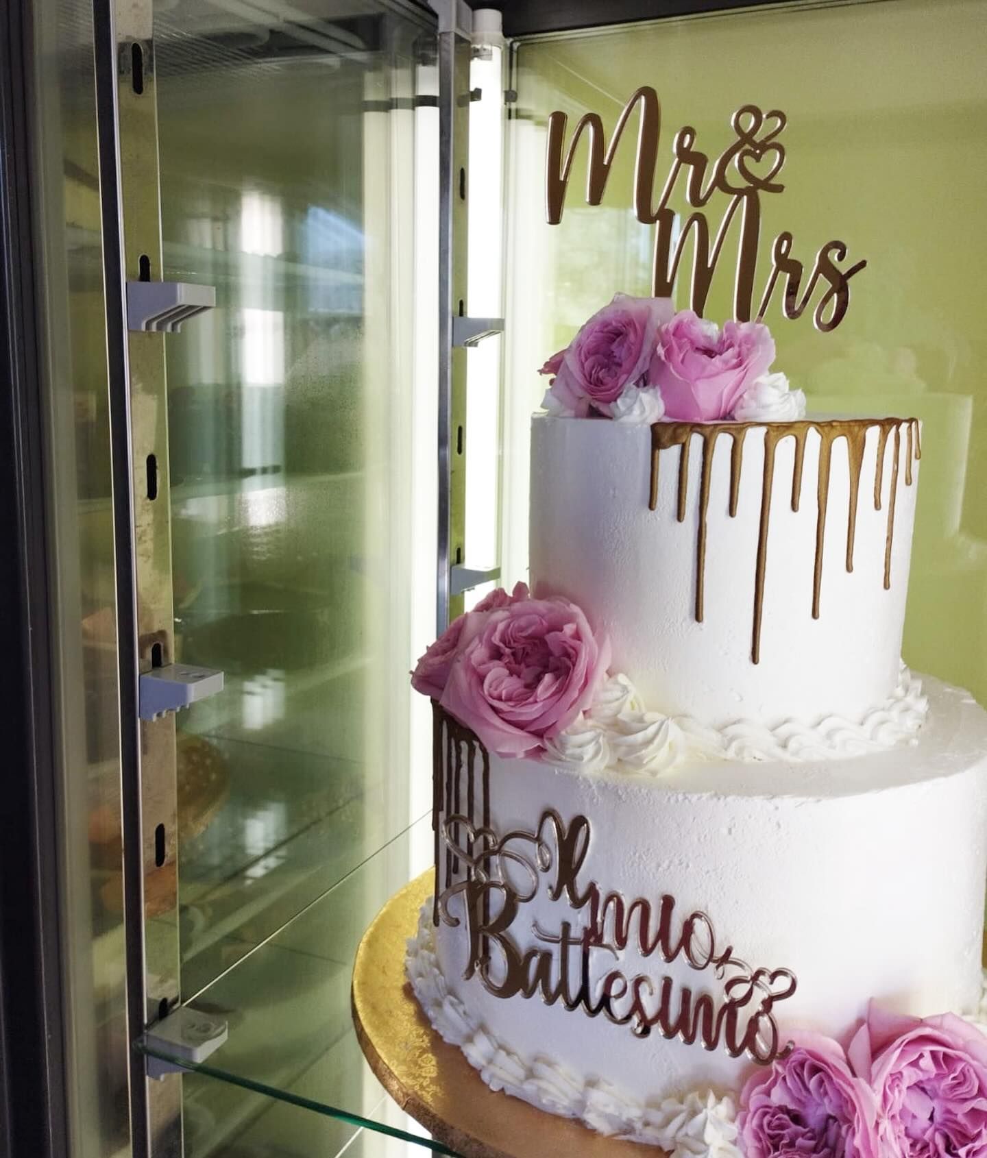 Una torta bianca con fiori rosa e le parole mr e mrs sopra