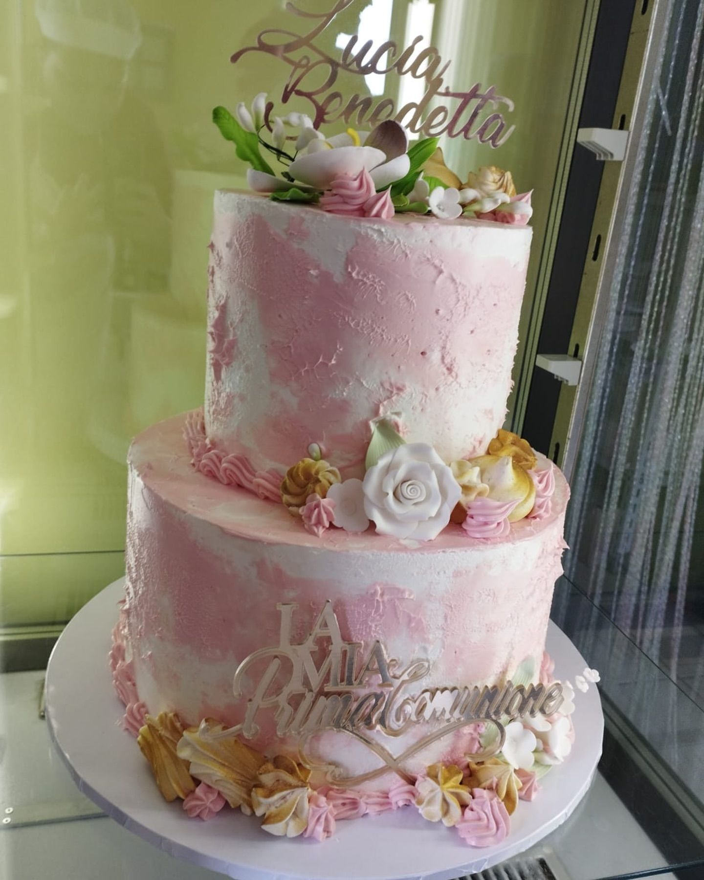 Una torta rosa e bianca con dei fiori sopra