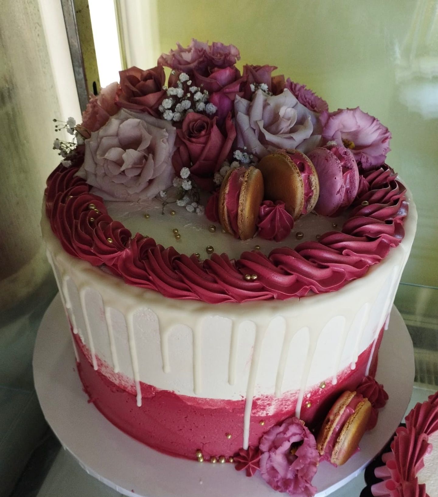 Una torta con glassa rosa e fiori sopra