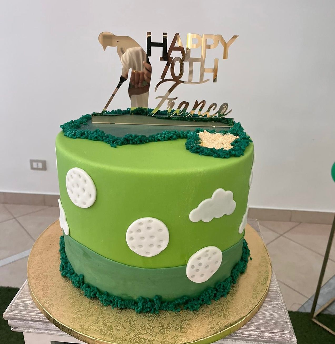 Una torta verde con pois bianchi e un topper con la scritta 