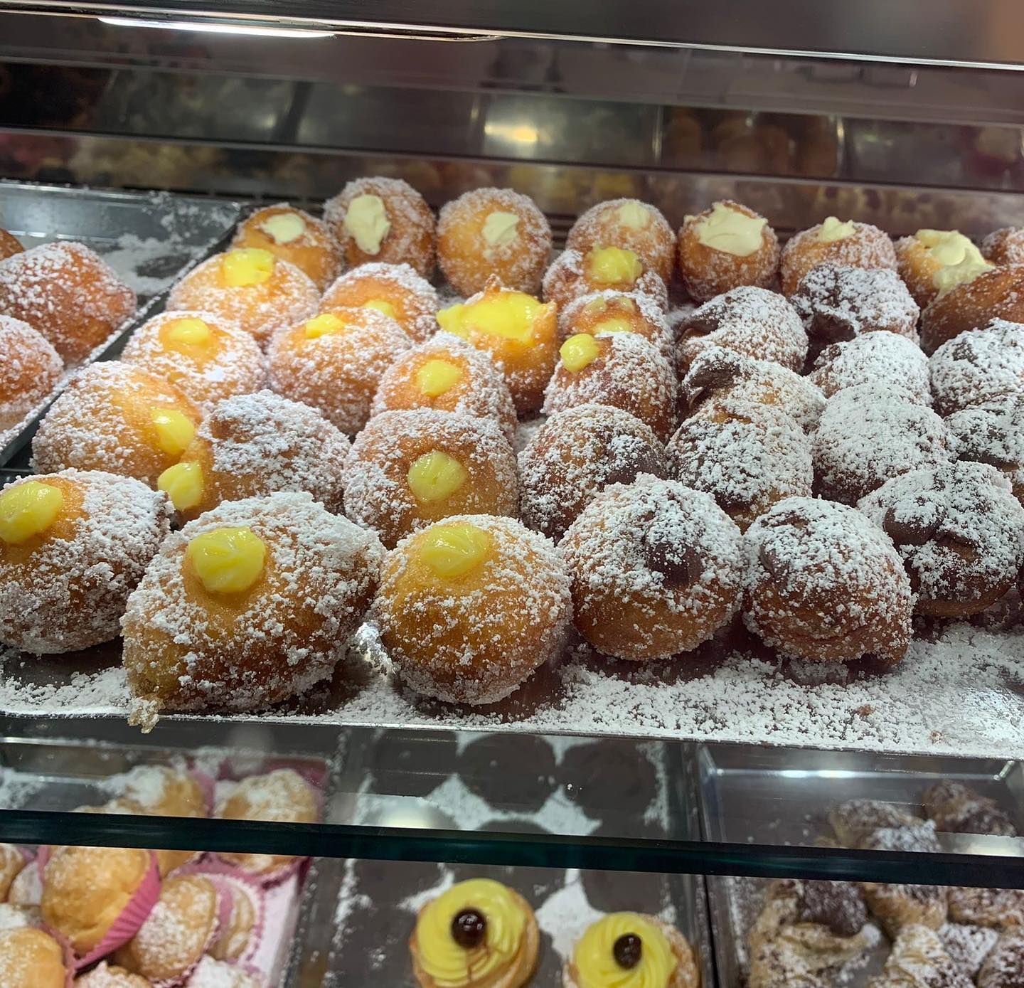 Una vetrina piena di una varietà di pasticcini ricoperti di zucchero a velo
