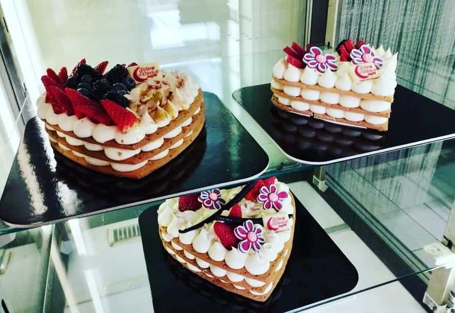 Tre torte a forma di cuore sono appoggiate su uno scaffale di vetro.