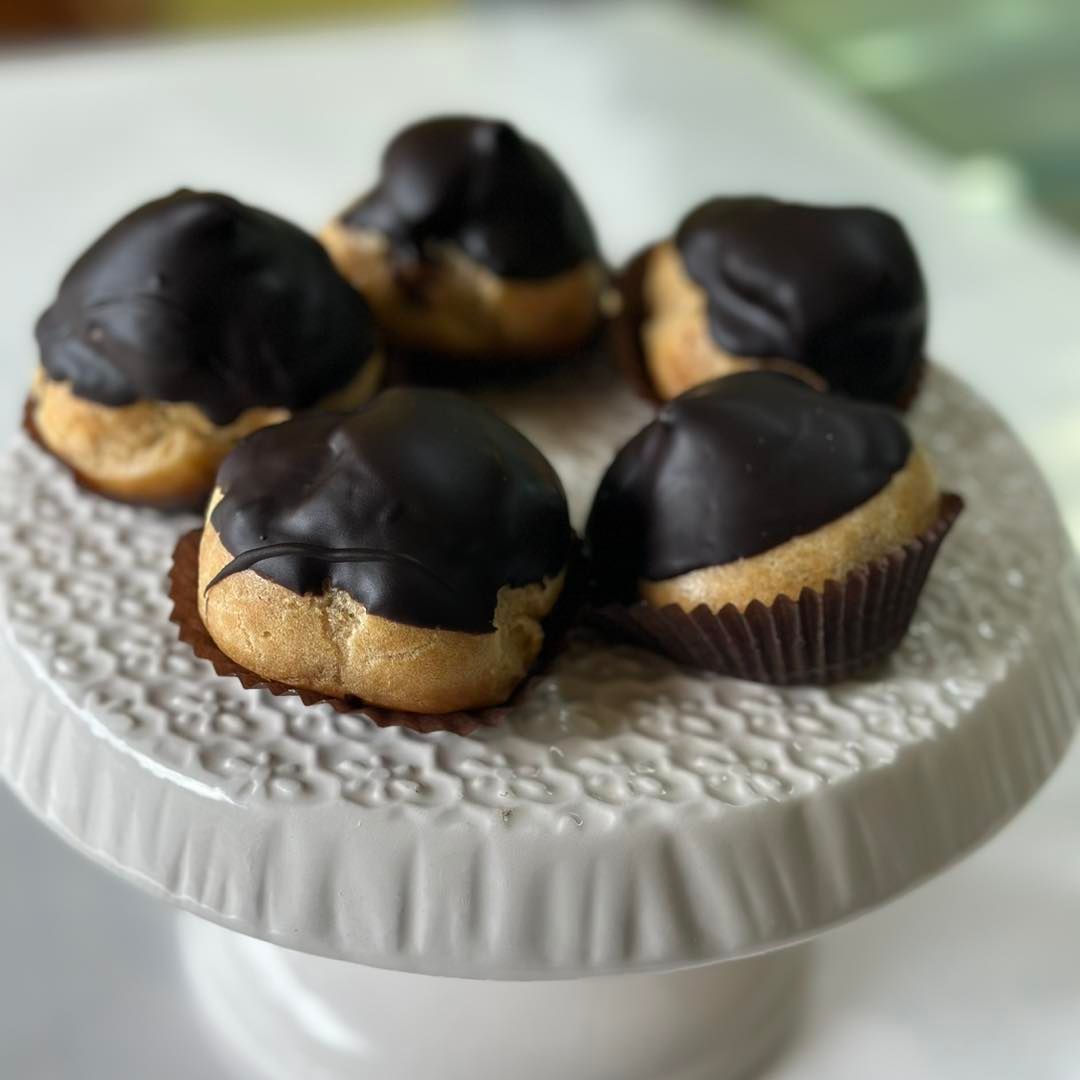Un'alzata bianca per torte con sopra dei cupcake ricoperti di cioccolato