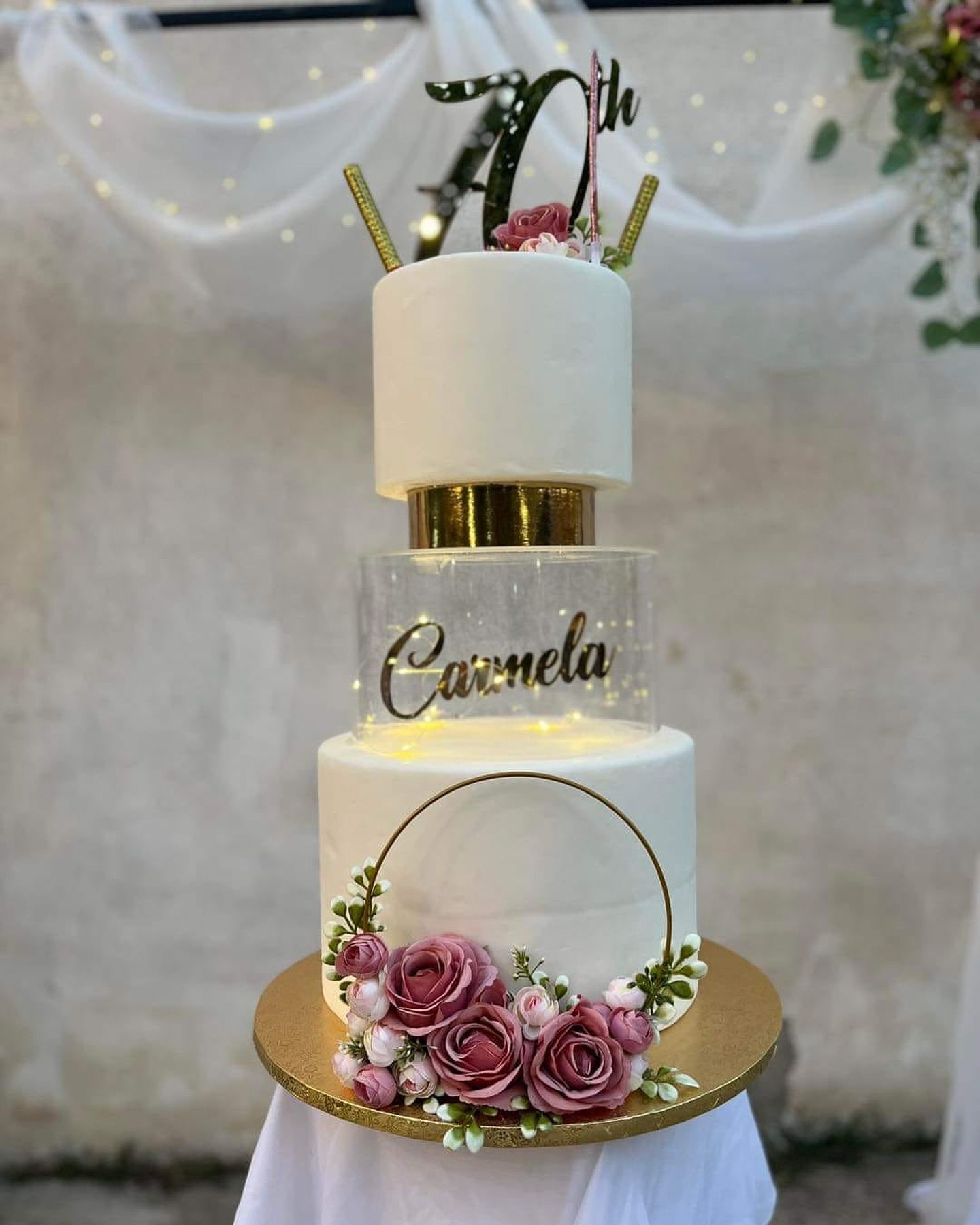 Una torta a tre piani con dei fiori sopra è appoggiata su un tavolo.