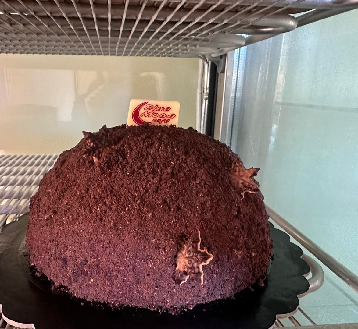 Una grande torta al cioccolato è appoggiata su un piatto nero
