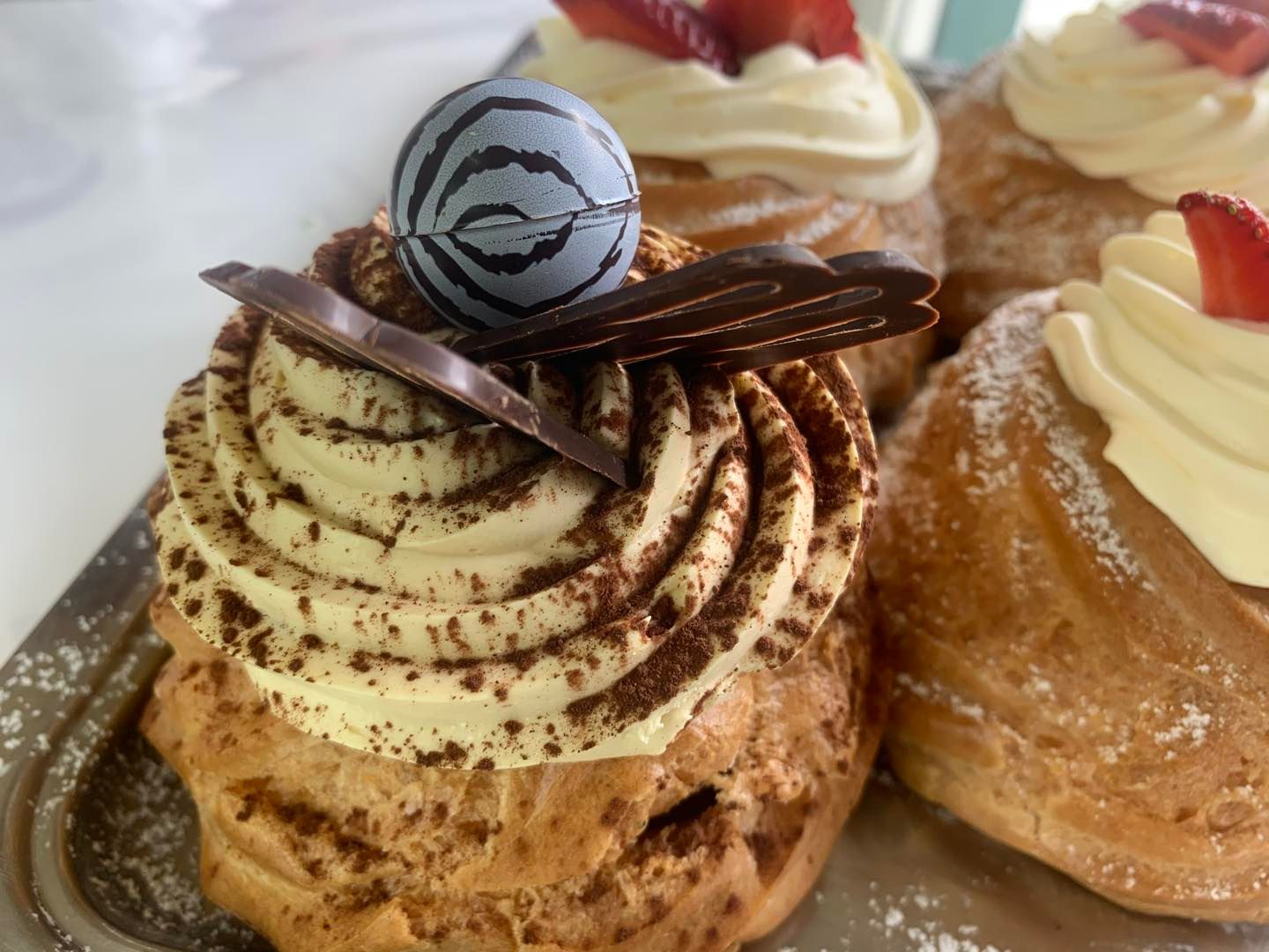 Primo piano di un dessert con panna montata e fragole su un vassoio.