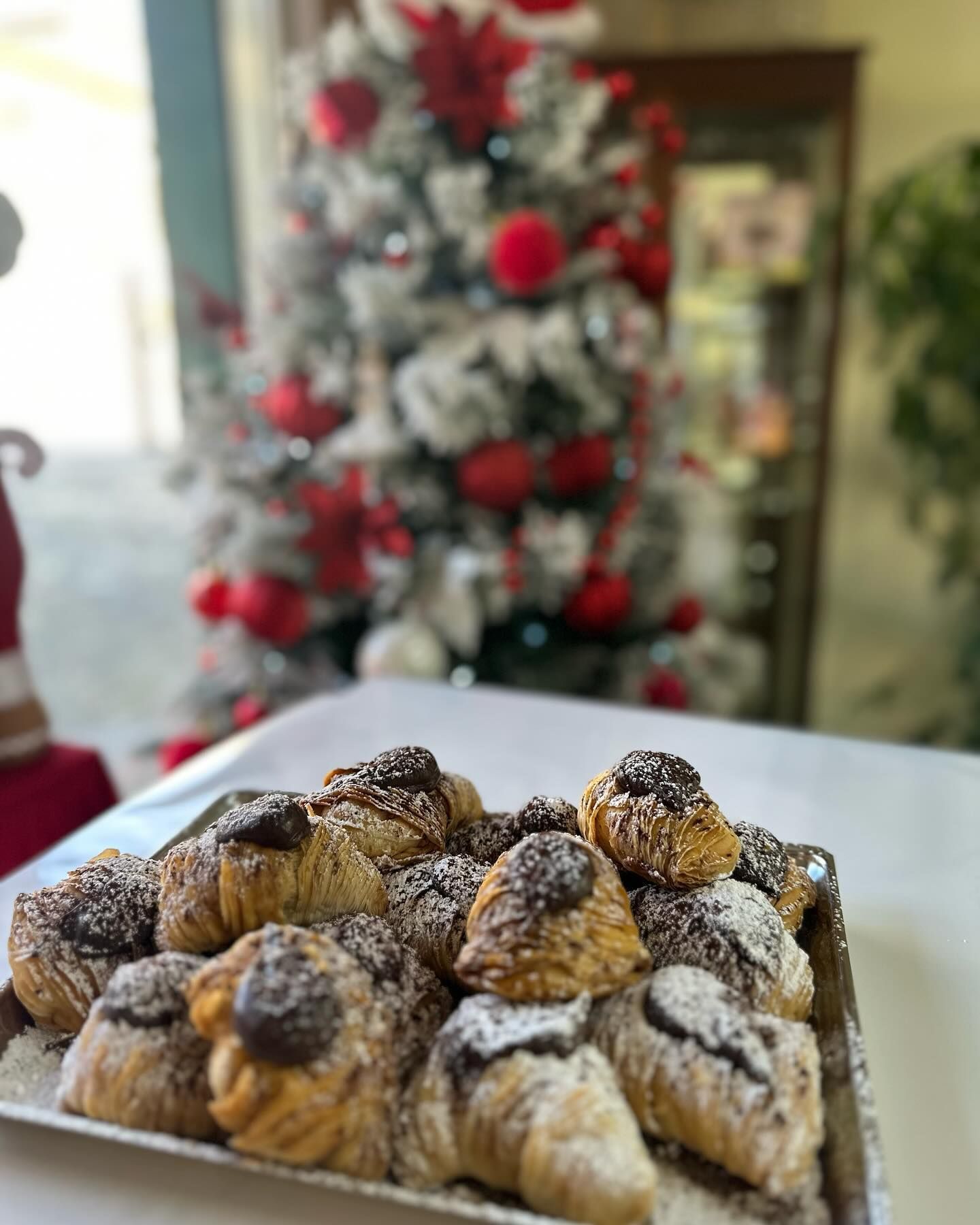 Un vassoio di pasticcini è appoggiato su un tavolo davanti all'albero di Natale.