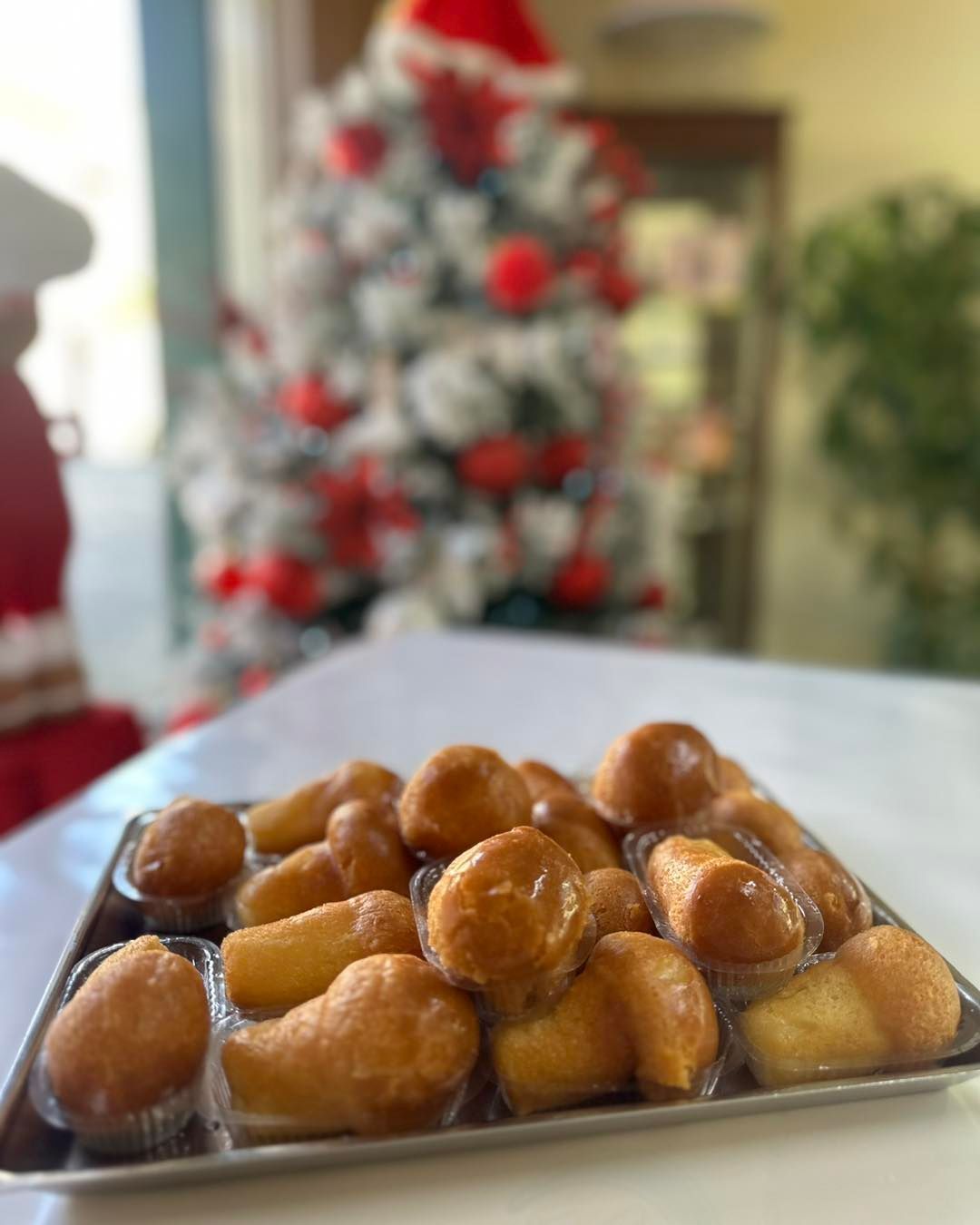 Un vassoio di ciambelle è appoggiato su un tavolo davanti all'albero di Natale.