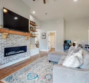 Living room with fireplace, large TV, gray sofa, and area rug.