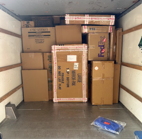 Packed moving truck interior with stacked cardboard boxes and a blue item on the floor