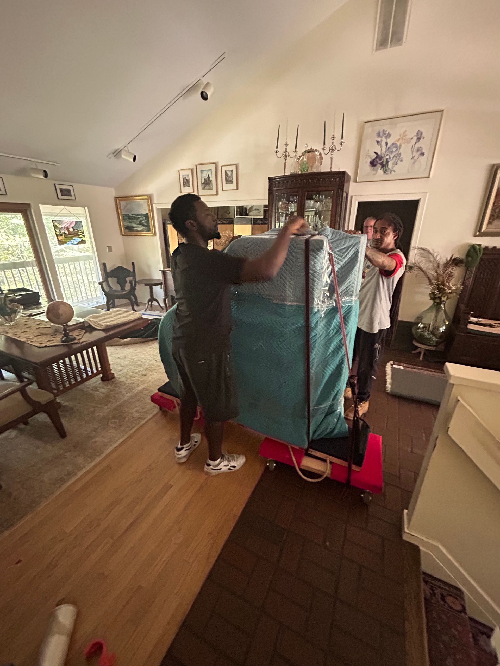 A group of people are moving a piano in a living room.