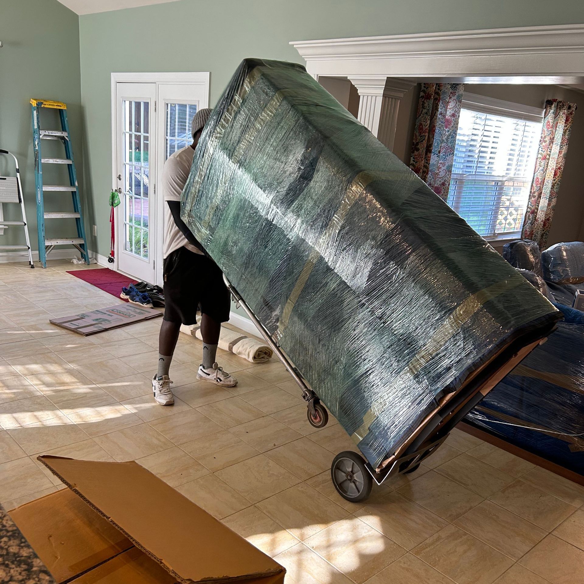 A man is carrying a large piece of furniture on a cart.