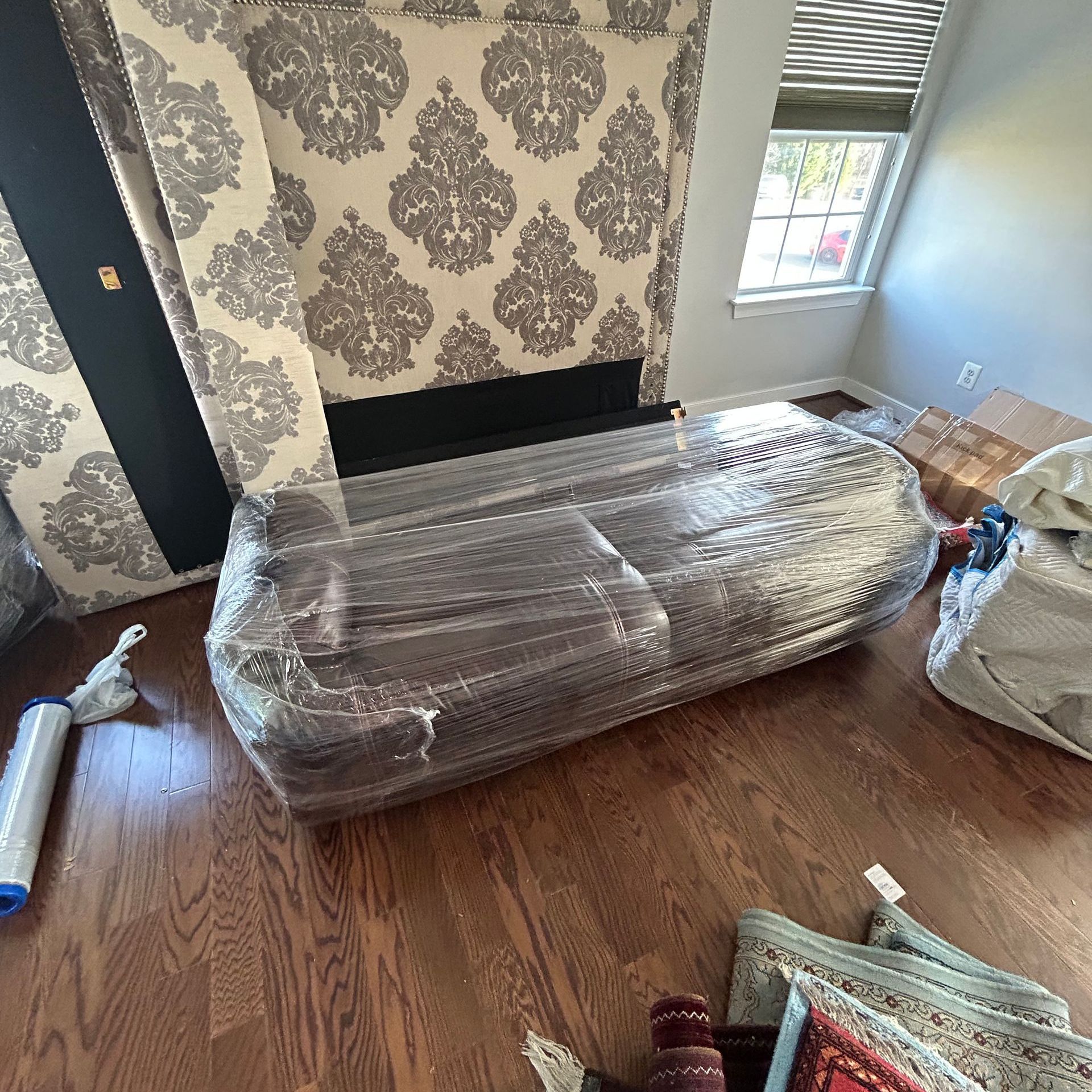 A couch is wrapped in plastic wrap in a living room.