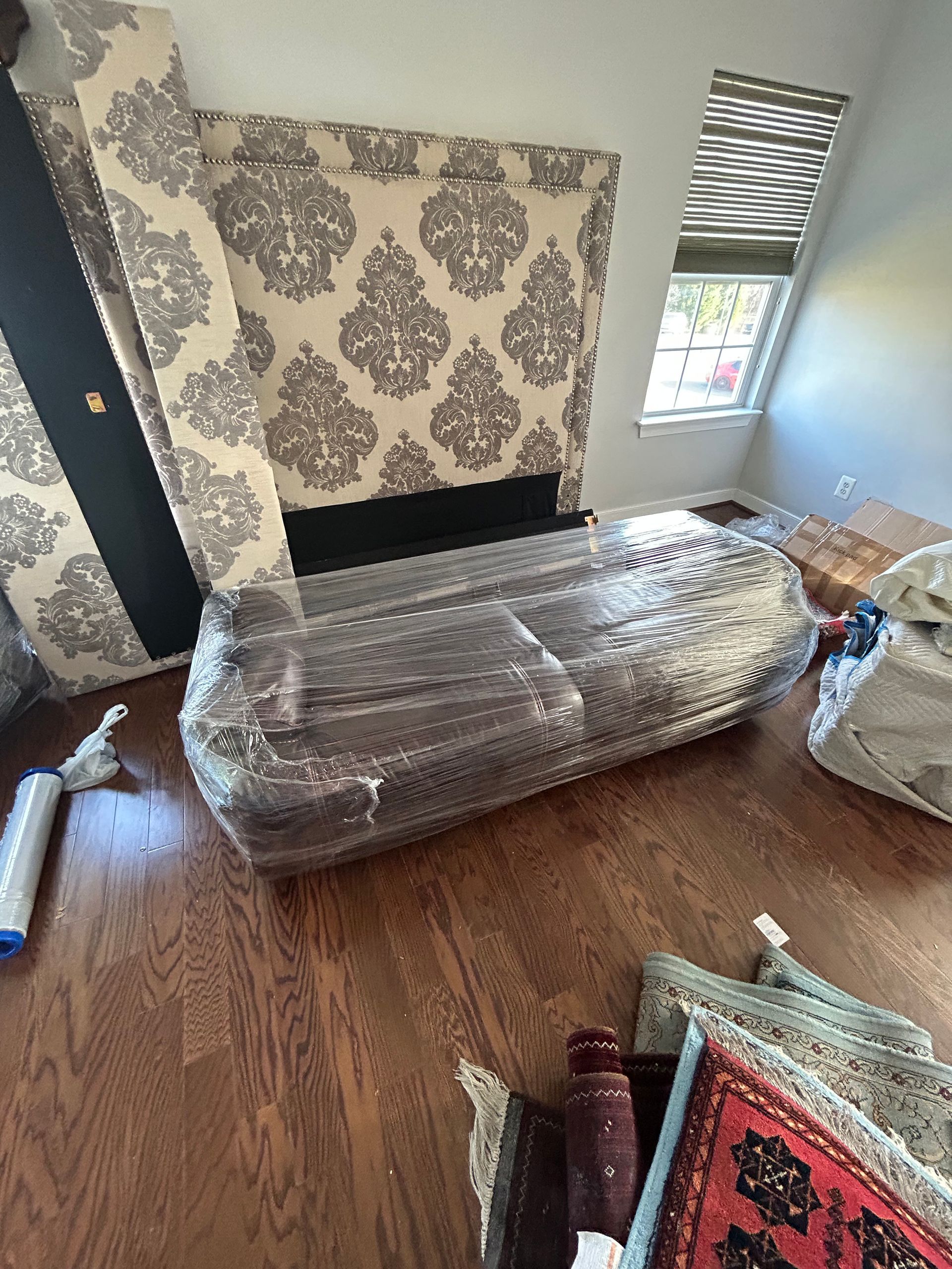 A living room with a couch wrapped in plastic and a fireplace.