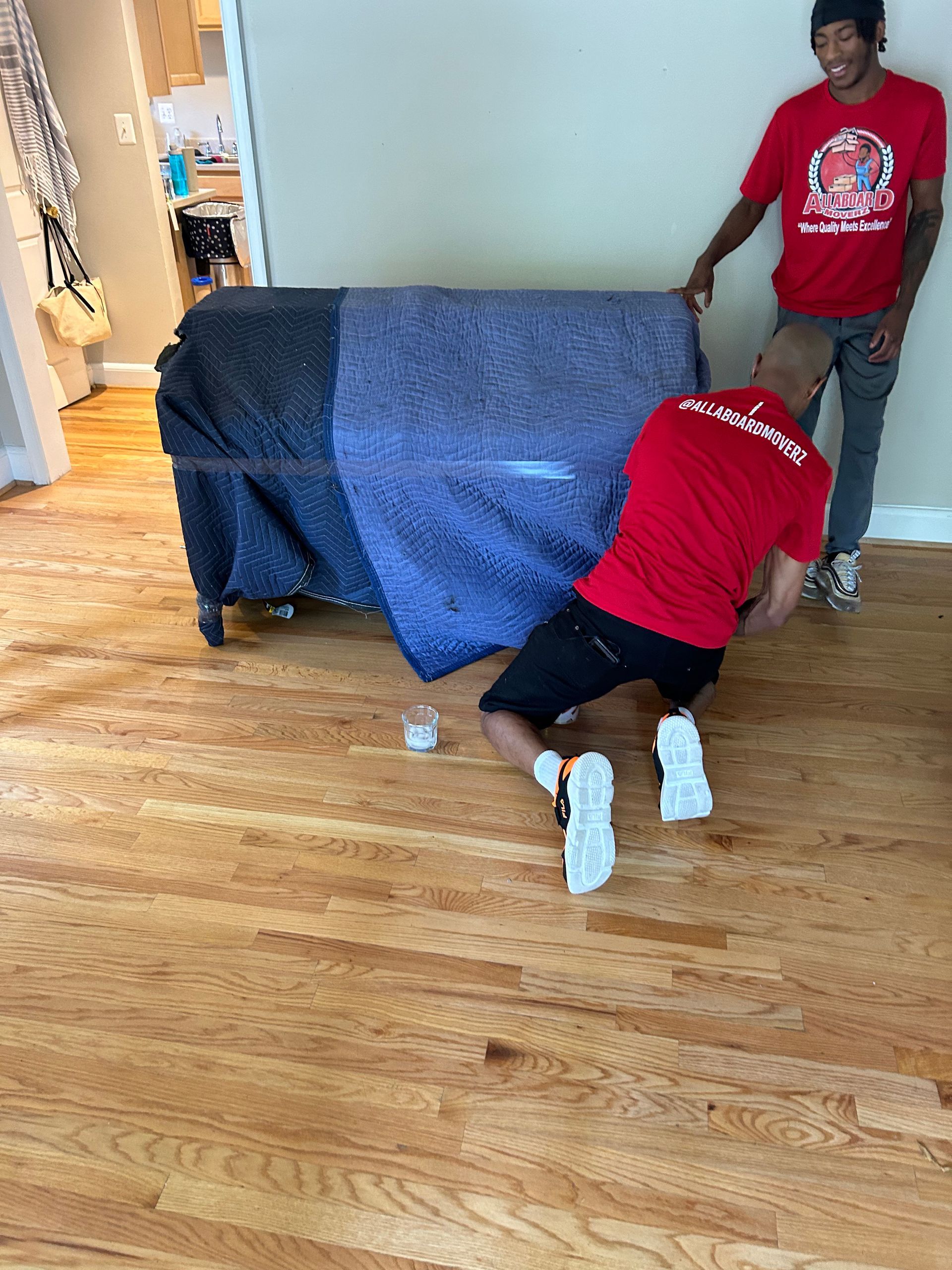 Two men are moving a couch in a living room.