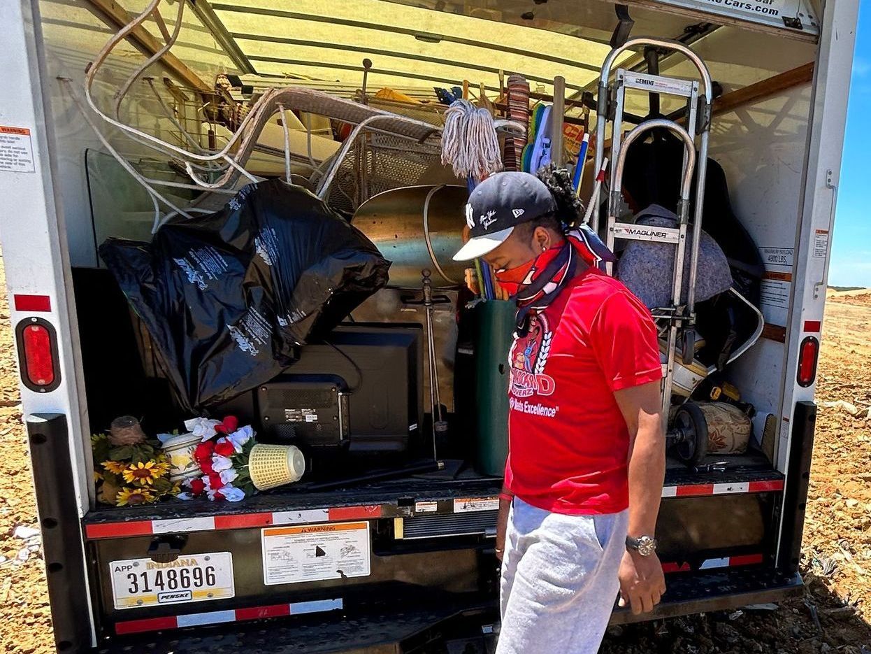 A man is standing in front of a truck with the back door open.