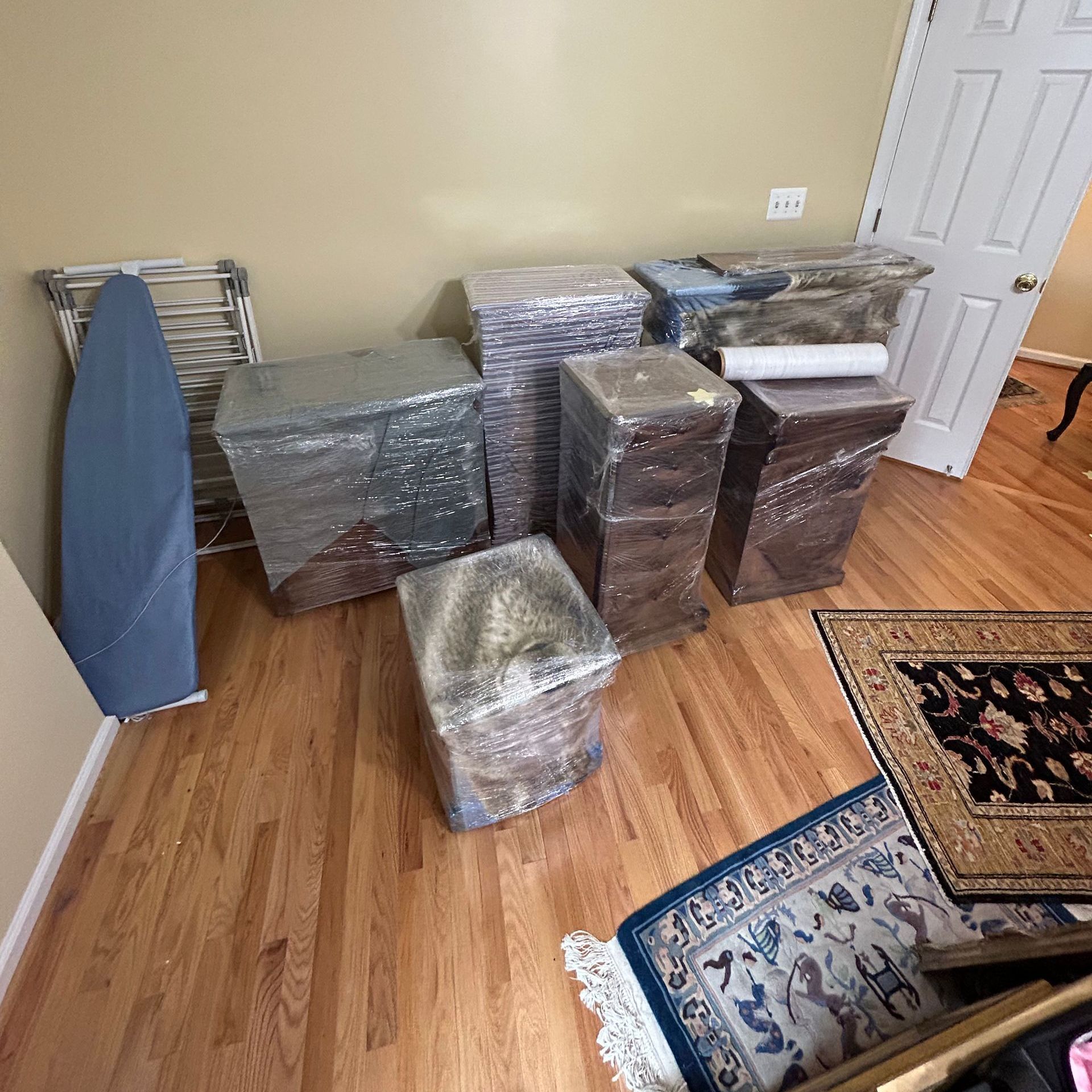 A room filled with boxes wrapped in plastic and a rug.