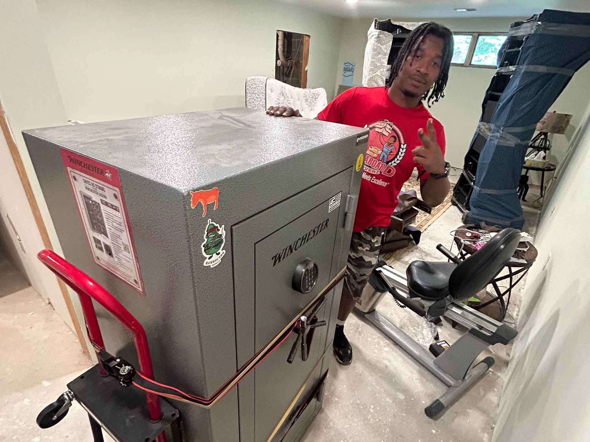 A man is standing next to a large safe on a dolly.