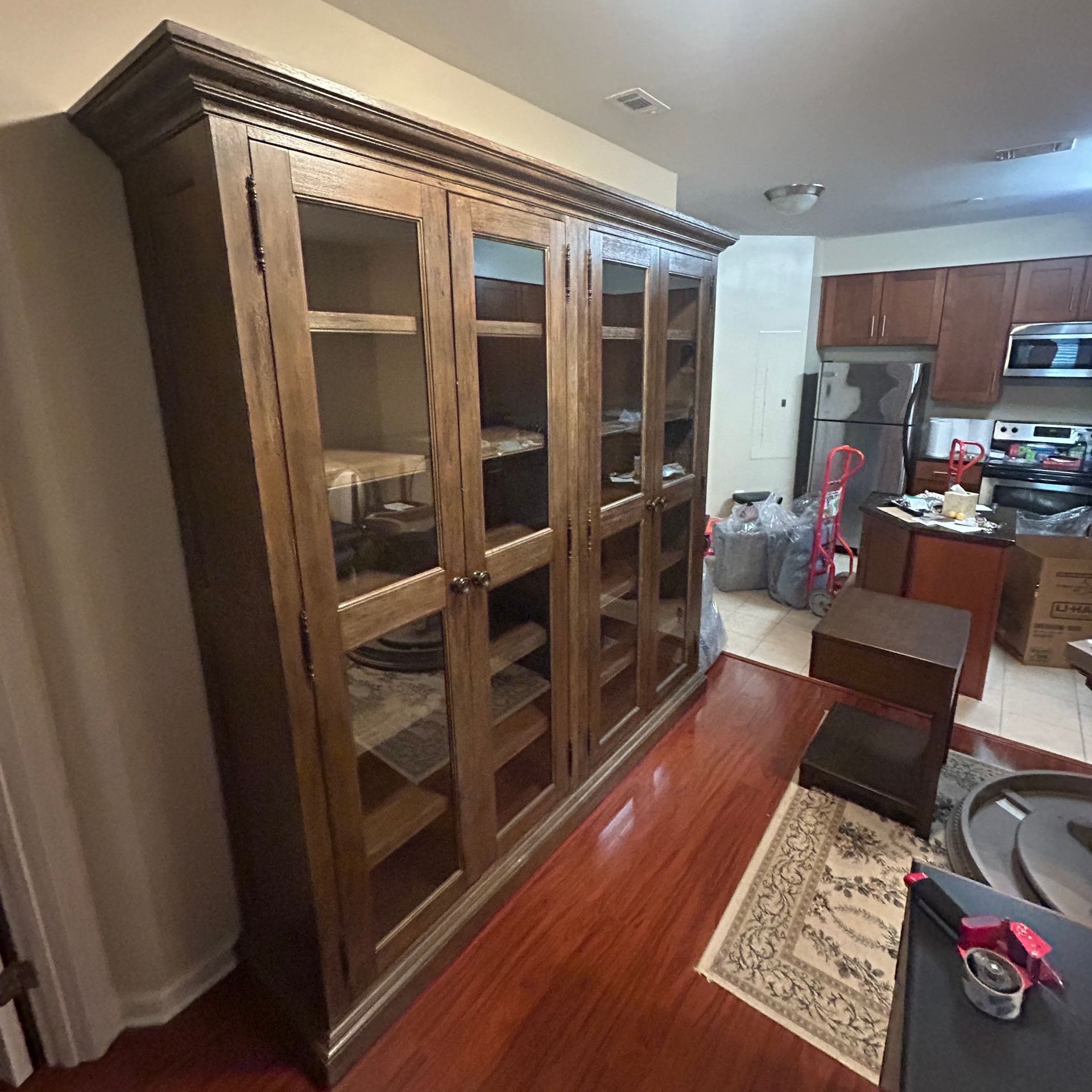 A large wooden cabinet with glass doors in a living room.