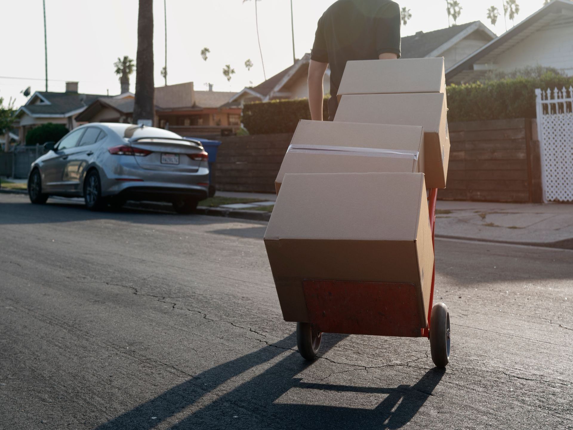 A man is pushing a cart full of cardboard boxes down a street