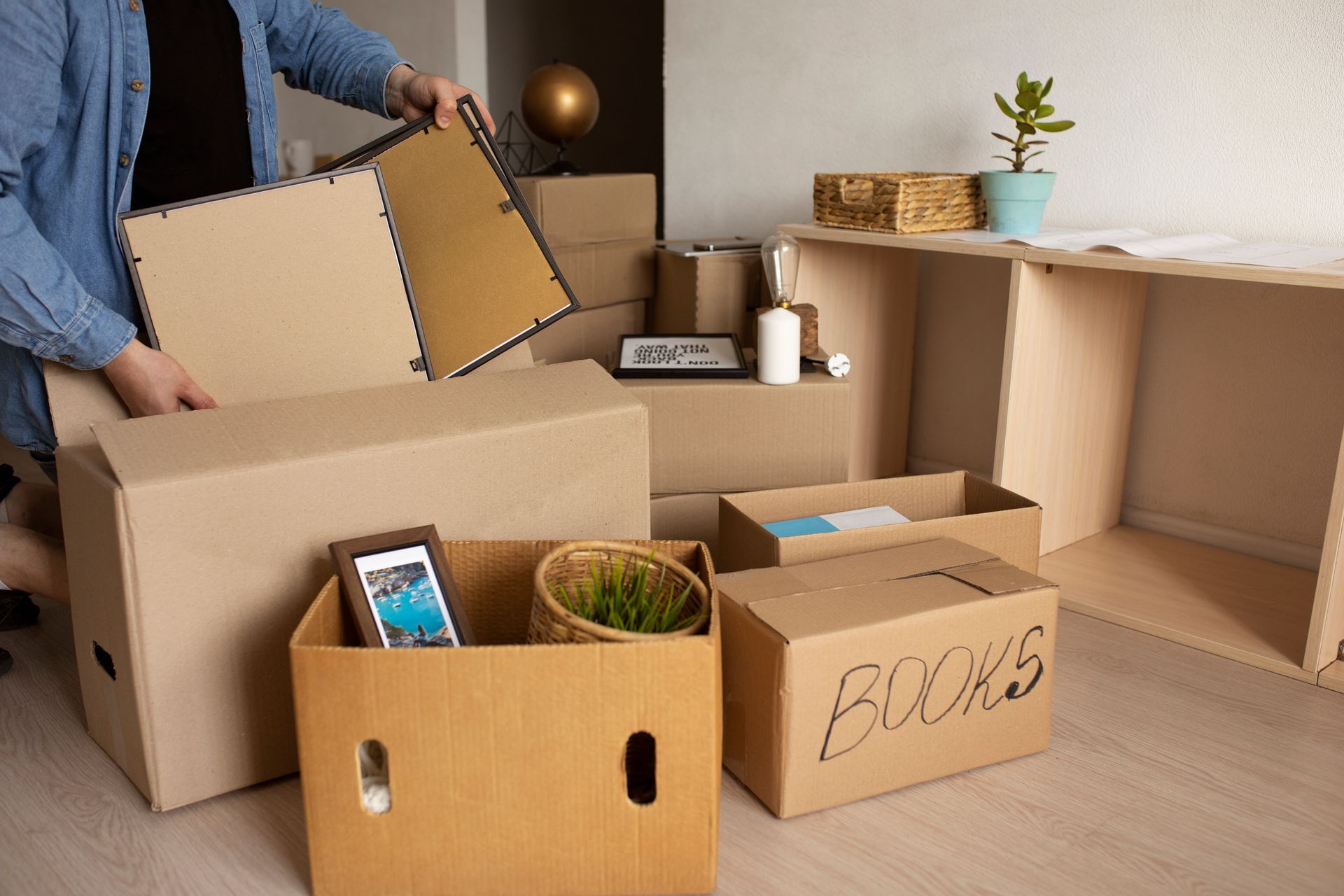 A man is packing boxes in a living room.