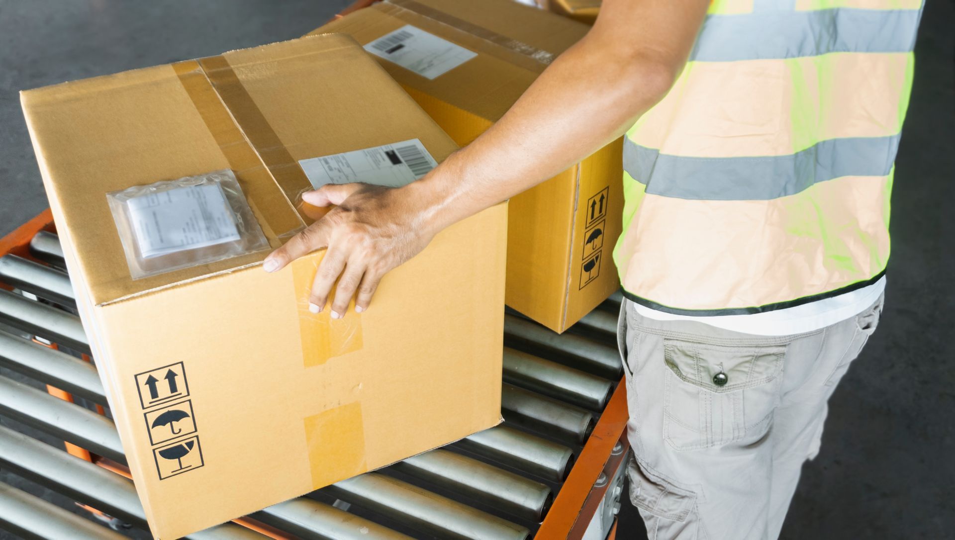 A man is holding a cardboard box on a conveyor belt.