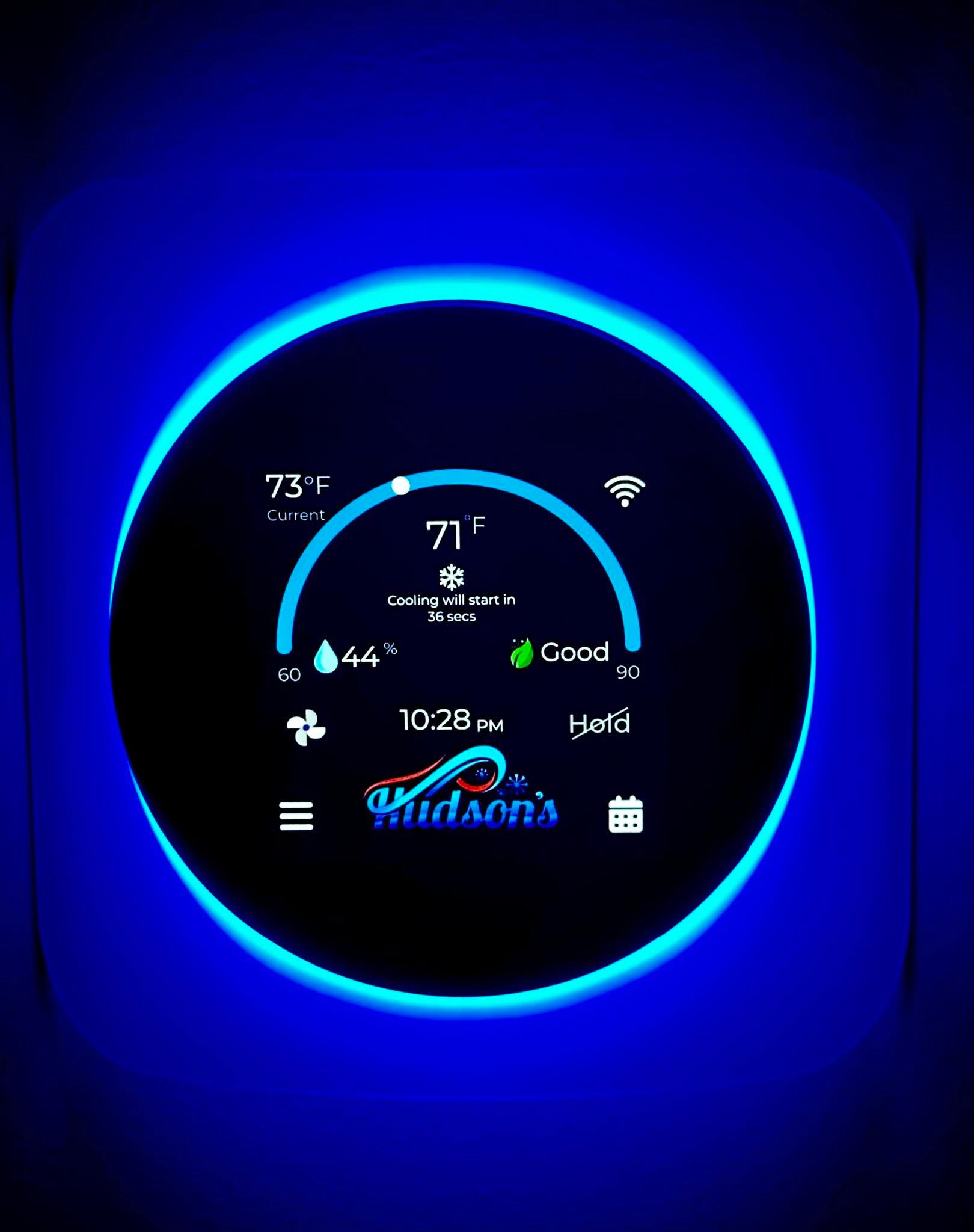 Smart thermostat, blue backlit, displaying temperature at 71 degrees, with Wi-Fi indicator and Hudson's logo.