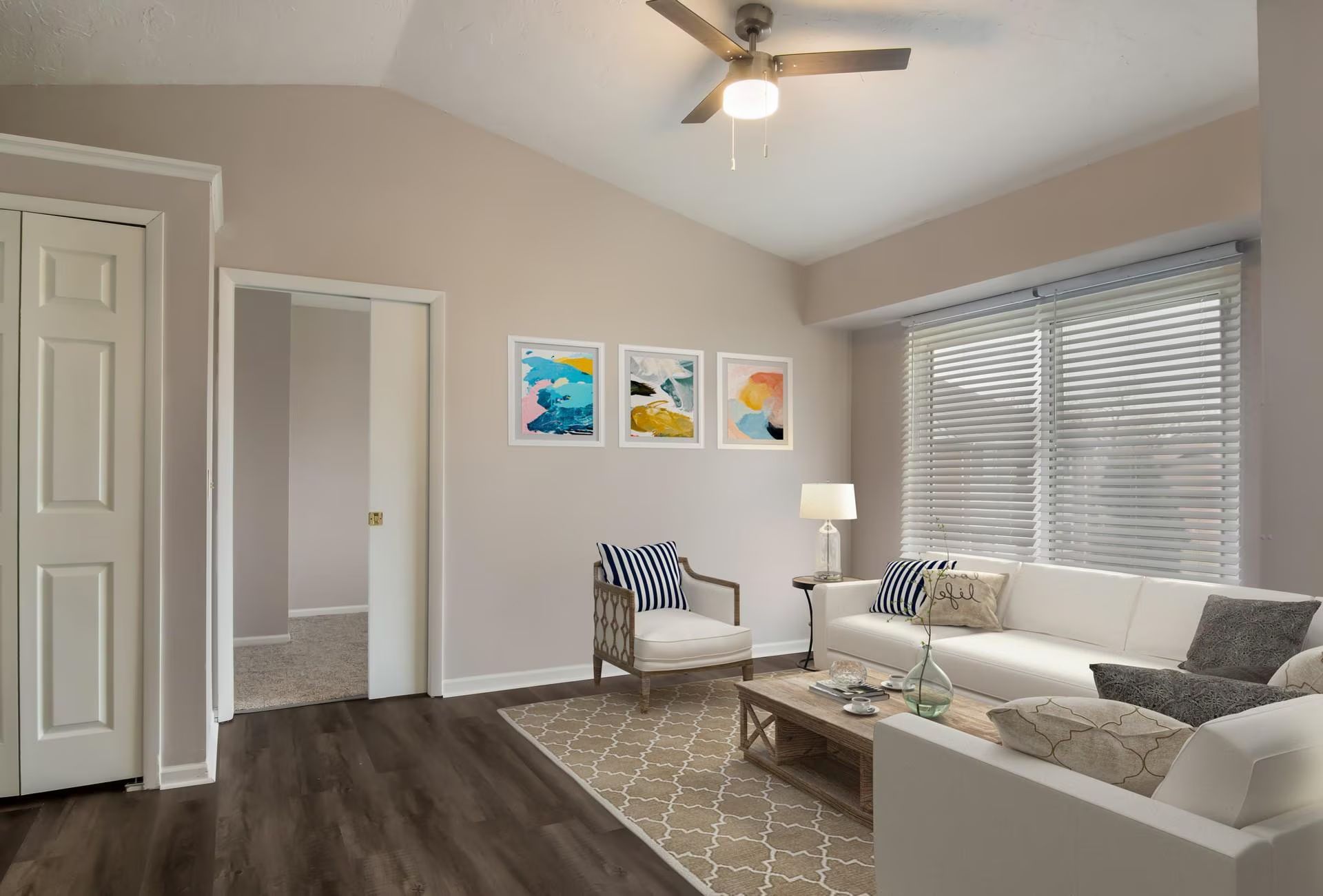 Living room with white sofa, artwork, chair, and coffee table.