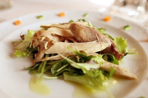 Insalata con pesce chiaro tagliato a fette su un piatto bianco; sono visibili le verdure e i pezzetti di carota.