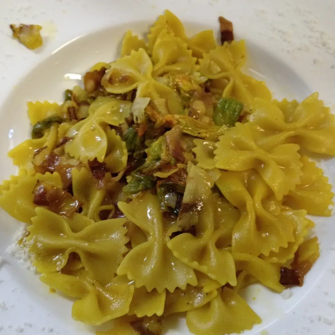 Pasta a farfalla con condimenti saporiti su un piatto bianco.