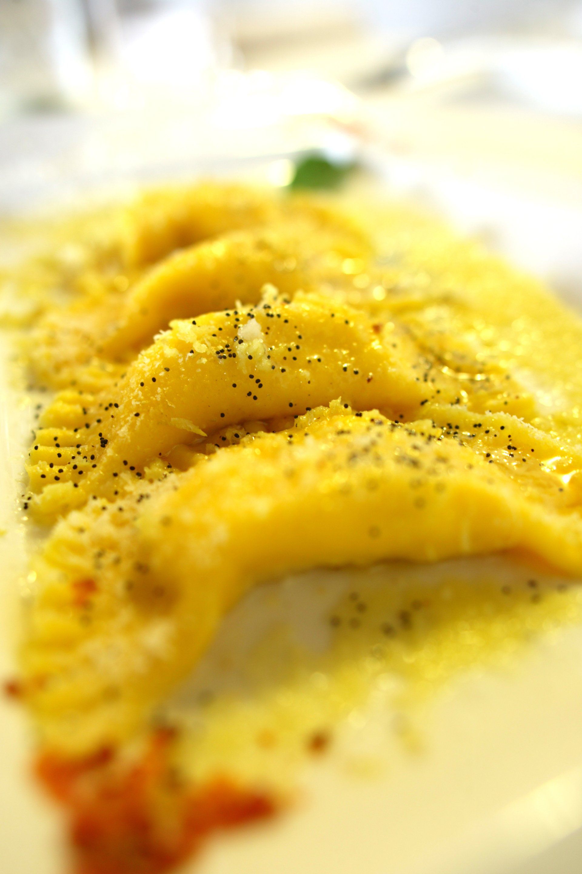 Ravioli gialli, leggermente pepati, su un piatto bianco.