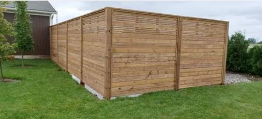 Wooden privacy fence in a backyard with green grass.