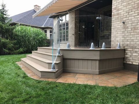 Outdoor patio with steps, glass railing, and attached shower.