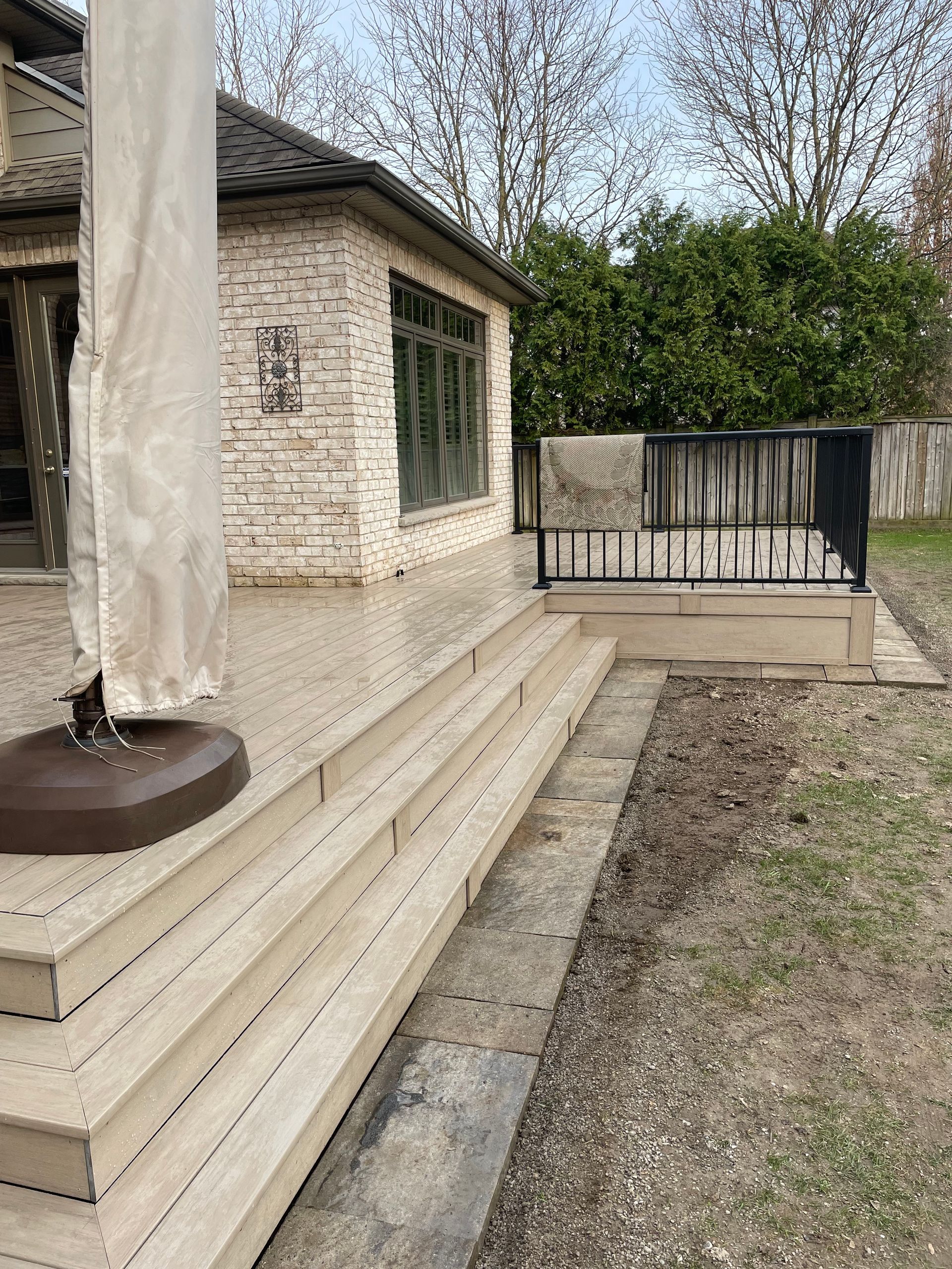 Deck with steps leading to a raised area, next to a building with stone siding.
