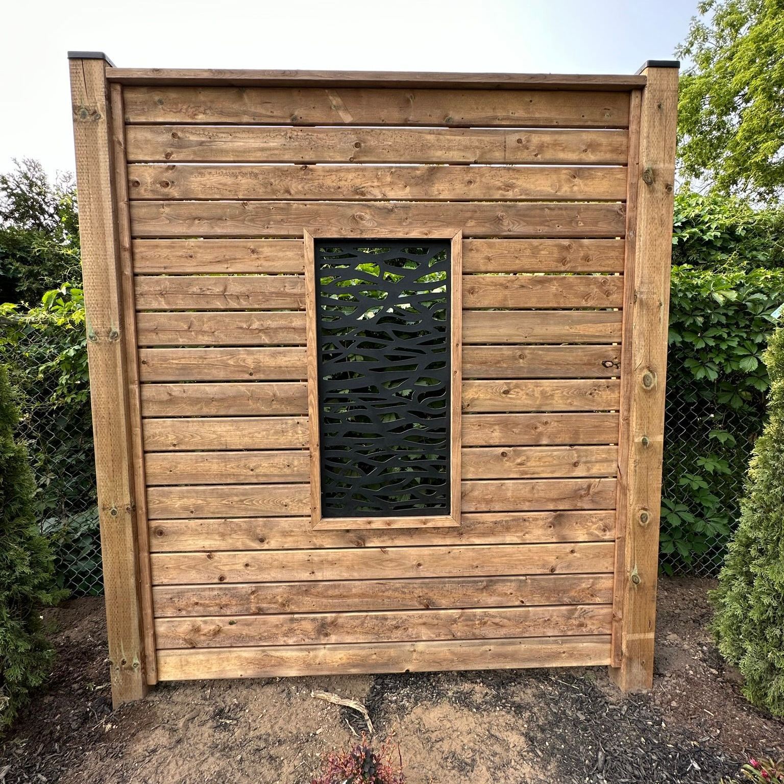 Wooden privacy screen with a decorative window.