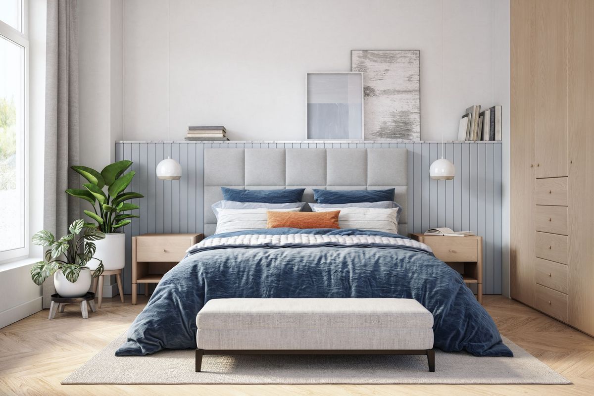 A bedroom with a bed , nightstands , a bench and a window.