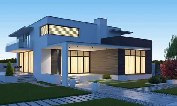 A modern house with a lot of windows is lit up at night.