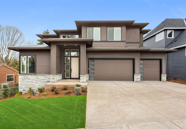 A large house with two garage doors and a driveway in front of it.