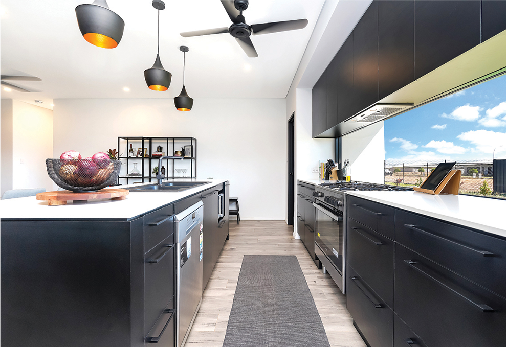 Modern black and white kitchen with island, overhead lighting, and a view of the sky.