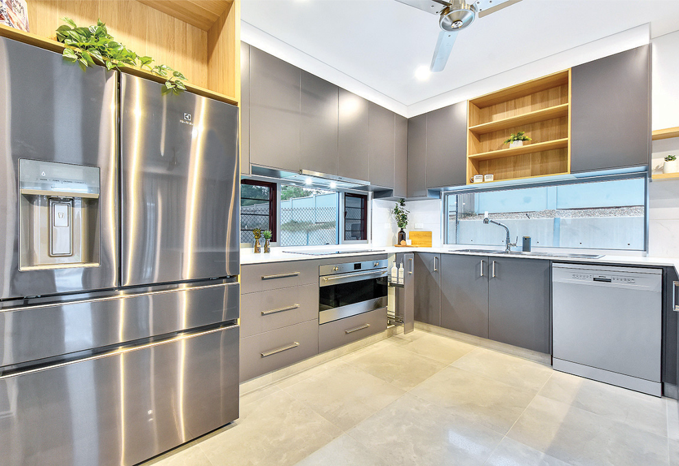 Modern gray kitchen with stainless steel appliances, cabinets, and large windows overlooking an outdoor scene.