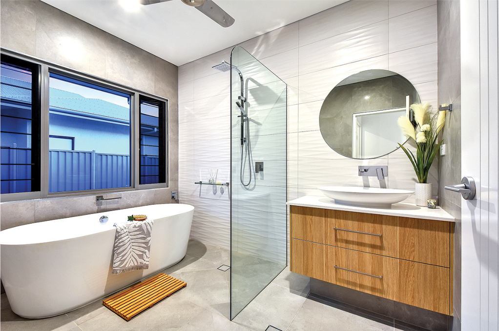 Modern bathroom with freestanding tub, glass shower, wooden vanity, and round mirror.