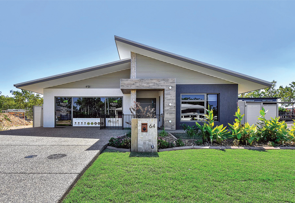 Modern one-story house with a slanted roof, gray and white facade, green lawn, and driveway.
