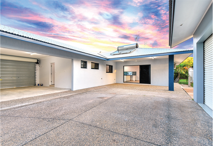 Exterior of a white house with a gray garage door and blue accents, against a colorful sunset.