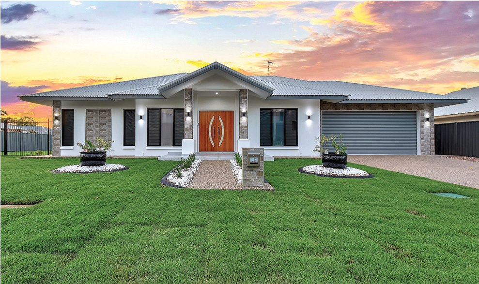 Modern white house with a green lawn at sunset.