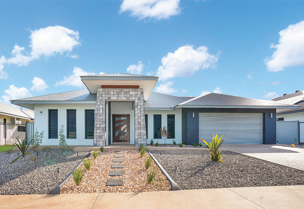 Modern home exterior with stone facade entrance, grey roof, and blue sky.