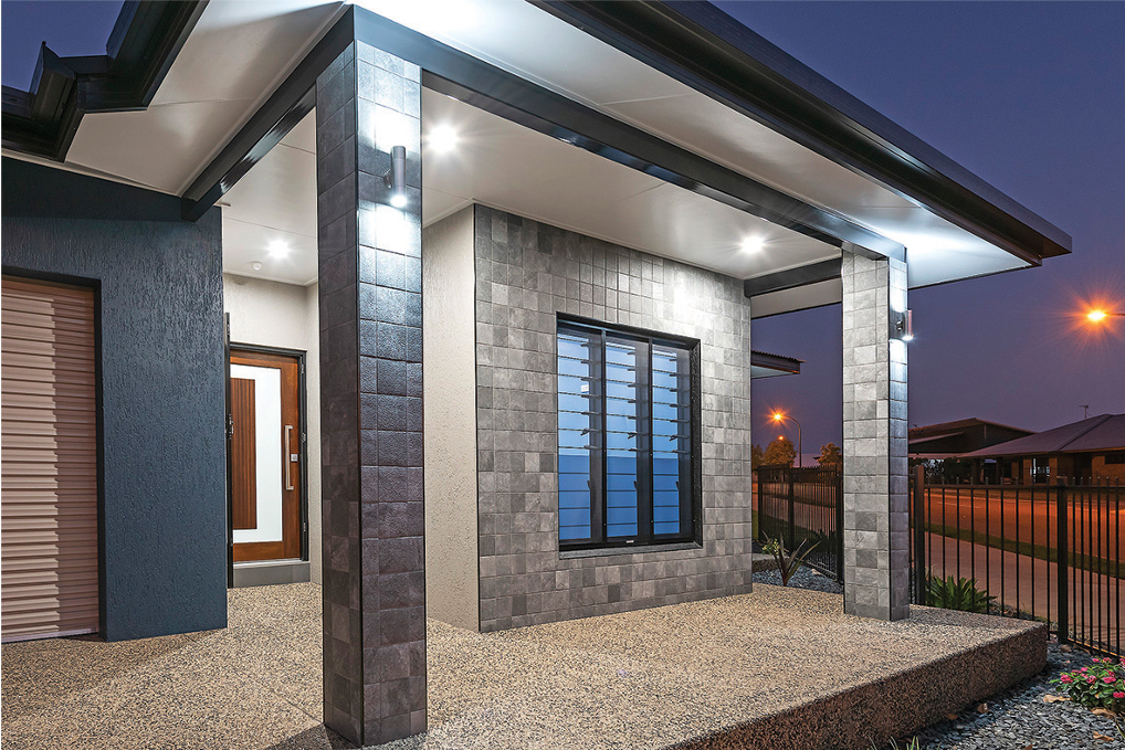 Modern home exterior with stone columns, textured walls, and a dark trim.