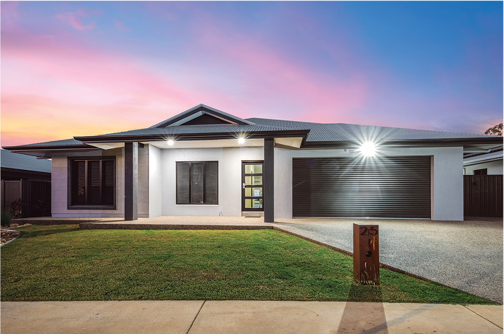 Modern single-story house with black garage door, front lawn, and colorful sky at sunset.