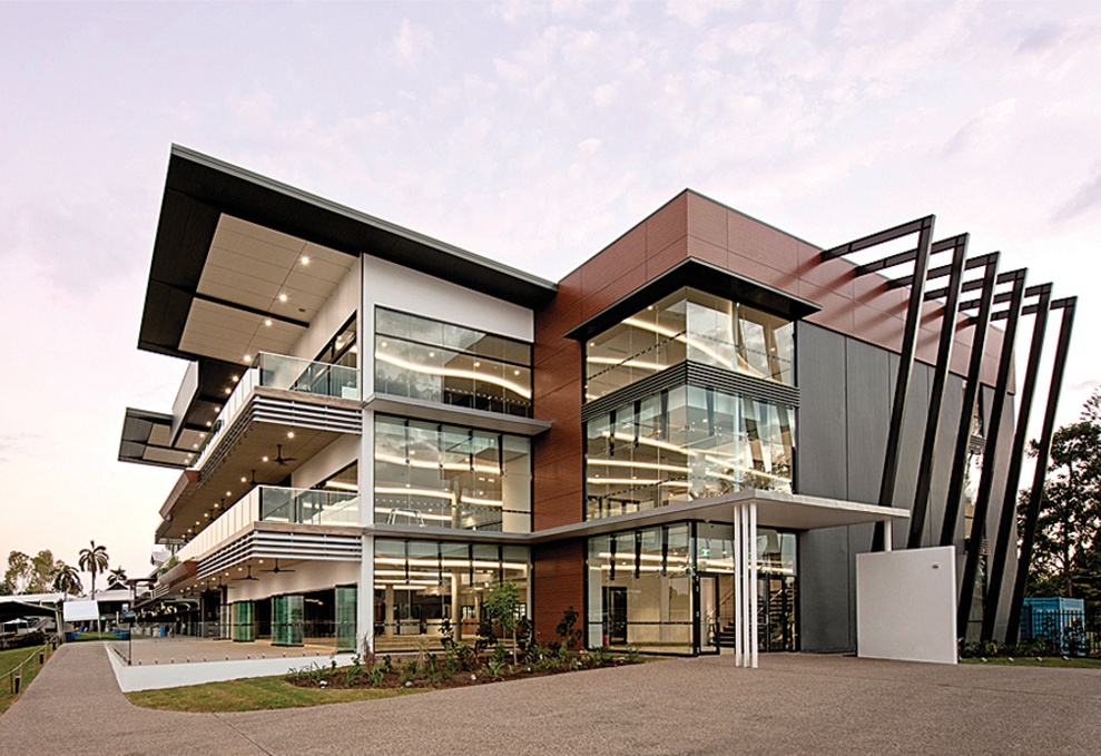 Modern three-story building with glass windows and a geometric facade; evening light.