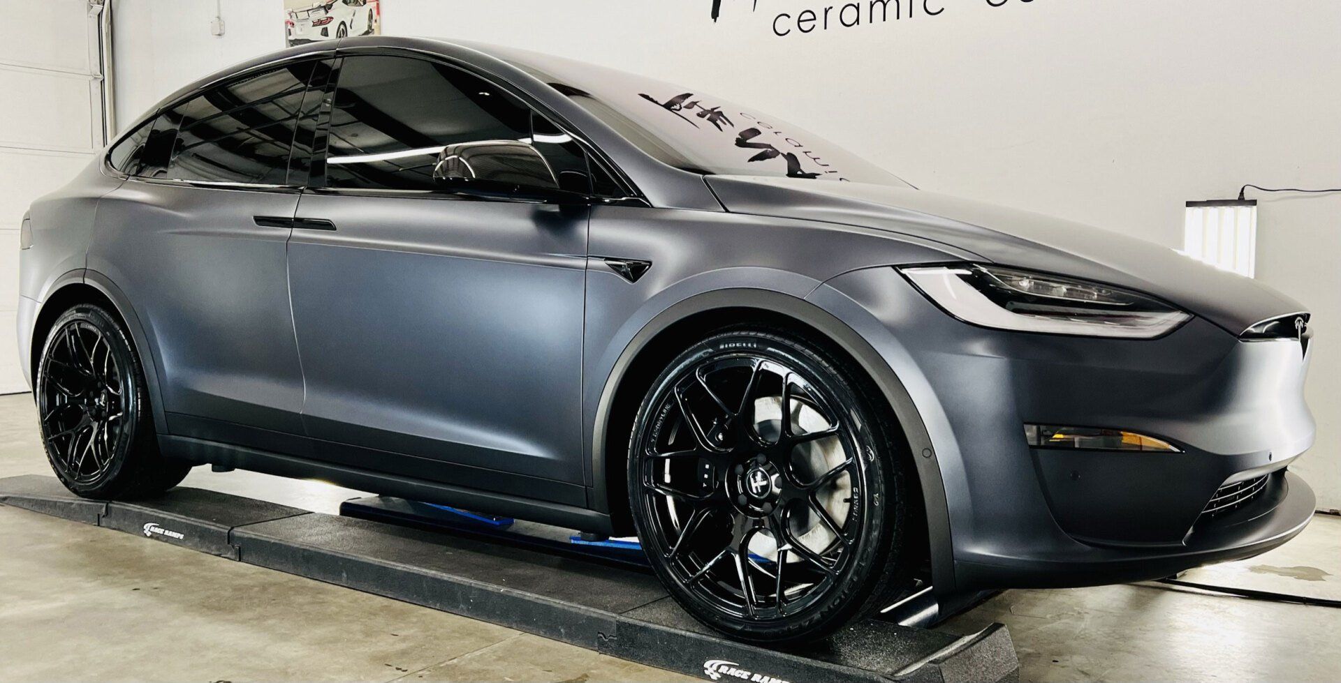 A tesla model x is parked on a lift in a garage.