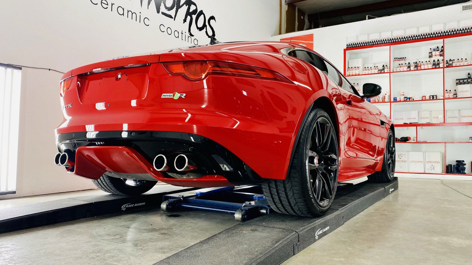 A red sports car is sitting on a lift in a garage.
